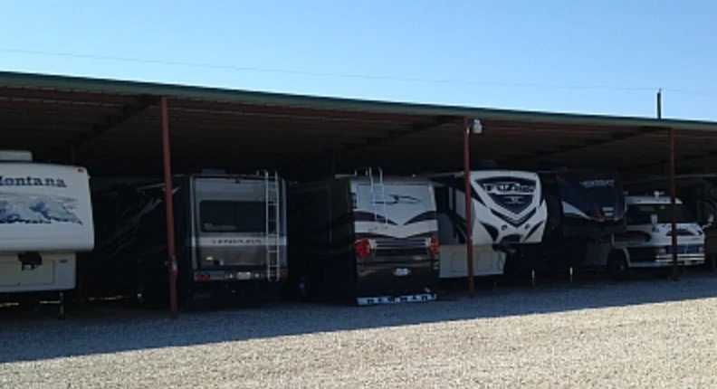 A covered row at RV Storage and More with RVs and trailers parked in their bays