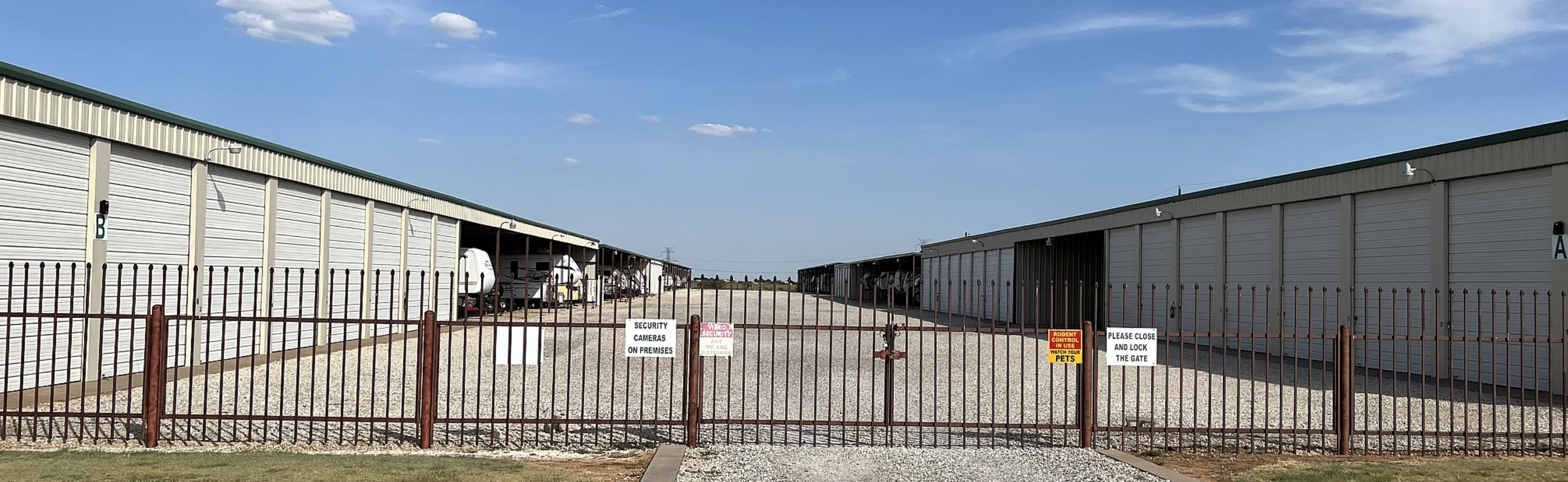 The gated front entrance of RV Storage and More off Highway 79, between two long rows of storage buildings